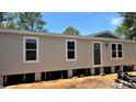 New single-story home featuring a neutral exterior, white-trimmed windows, and a front door, set against a bright blue sky at 10040 Lake Dr, Weeki Wachee, FL 34613