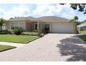Beautiful home with a brick-paved driveway, lush landscaping, and an attached two-car garage at 11014 Peking Pl, Tampa, FL 33624