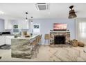 Open-concept living room and kitchen with modern finishes, stone fireplace, and ample natural light at 1210 Bay Palm Blvd, Indian Rocks Beach, FL 33785