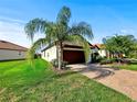 A view of the front exterior showing the attached two-car garage and the adjacent green lawn at 16913 Anchor Root St, Wimauma, FL 33598