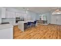 Open-concept kitchen featuring a large island, white cabinets, stainless steel appliances, and modern lighting at 18444 Eastwyck Dr, Tampa, FL 33647