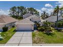 Inviting single-Gathering home with lush landscaping, two-car garage, and a well-kept lawn on a sunny day at 2614 Hawk Roost Ct, Holiday, FL 34691