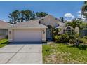 Lovely single-Gathering home featuring a two-car garage, arched entry, and manicured landscaping at 2614 Hawk Roost Ct, Holiday, FL 34691