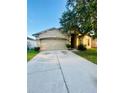 Beige two-story home with a two-car garage and a concrete driveway at 30742 Birdhouse Dr, Wesley Chapel, FL 33545