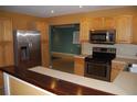A kitchen boasts stainless steel appliances, wooden cabinetry, and a bar overlooking an open living space at 6326 55Th N Ave, St Petersburg, FL 33709