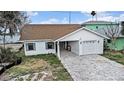 Charming waterfront home with attached garage and brick paved driveway on a sunny day at 811 Bay Point Dr, Madeira Beach, FL 33708