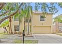 Charming two-story home featuring a two car garage, light yellow paint and mature landscaping and palm trees at 10311 Frog Pond Dr, Riverview, FL 33569