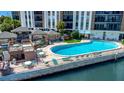 Beautiful community pool with patio furniture and shaded seating areas in a waterfront setting at 10355 Paradise Blvd # 502, Treasure Island, FL 33706