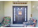 Covered porch showcasing a welcoming front door and cozy seating area with floral cushions at 11148 Hollander Ave, Hudson, FL 34667