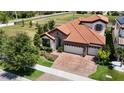 Beautiful home showcasing a tile roof, brick driveway, lush landscaping, and a serene neighborhood pond at 13706 Osprey Fern Ln, Riverview, FL 33569