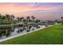 Waterfront backyard on a canal lined with docks, lush grass, and picturesque palm trees under a colorful sky at 1449 45Th Ne Ave, St Petersburg, FL 33703