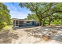 Single-story home with mature trees providing shade, plus a screened in porch, and blue front door at 2305 N 48Th St, Tampa, FL 33605