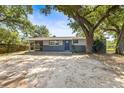 Single-story home with a blue front door, a screened in porch and a spacious unlandscaped front yard at 2305 N 48Th St, Tampa, FL 33605