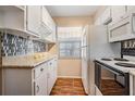 Functional kitchen with white cabinetry, neutral countertops, mosaic tile backsplash, and earth tone flooring at 3839 Trophy Blvd # 3839, New Port Richey, FL 34655