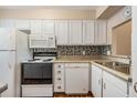 Well-lit kitchen with white appliances, cabinetry, mosaic backsplash, and stainless steel sink at 3839 Trophy Blvd # 3839, New Port Richey, FL 34655