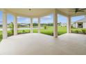 Relaxing covered patio overlooking a lush green lawn and a tranquil lake, perfect for outdoor entertaining at 4709 Isonzo Way, Wesley Chapel, FL 33543