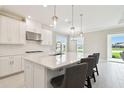 Modern kitchen boasts a center island with seating and pendant lighting, ideal for gatherings at 4709 Isonzo Way, Wesley Chapel, FL 33543