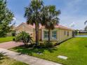 Charming yellow home with palm trees and bay window, showcasing curb appeal at 4821 Grand Banks Dr, Wimauma, FL 33598
