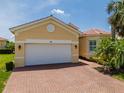 A yellow home with a white garage door and brick driveway offers a neat exterior at 4821 Grand Banks Dr, Wimauma, FL 33598