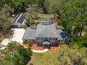 An aerial view of a two-story home with a pool, screened enclosure, lush landscaping and detached garage at 5305 Lenoir Ct, Plant City, FL 33566