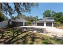 Spacious detached three-car garage and driveway with mature landscaping and a partially fenced yard at 5305 Lenoir Ct, Plant City, FL 33566