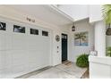 Close-up of townhome entrance with garage, door, modern light, painting, and welcome sign enhancing curb appeal at 9812 Indian Key Trl # 84, Seminole, FL 33776