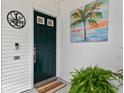 Stylish front door with green paint and palm tree art for curb appeal, complemented by lush greenery and a welcome mat at 9812 Indian Key Trl # 84, Seminole, FL 33776