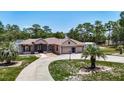 Inviting single-story home featuring a three-car garage, long driveway, and nicely landscaped grounds at 13110 Manistee Rd, Weeki Wachee, FL 34614