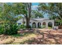 Single story home with arched walkway, lush landscaping and mature trees at 1514 Florida Ave, Palm Harbor, FL 34683