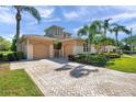 Inviting exterior with dual garages, a brick driveway, and lush tropical landscaping at 2407 Kensington Greens Dr, Sun City Center, FL 33573