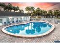 A bright and inviting community pool with lounge chairs sits next to a clubhouse under a colorful sky at 5048 Sunridge Palms Dr # 103, Tampa, FL 33617