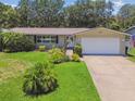 Welcoming single-story home featuring a manicured lawn, mature landscaping, and a two car garage at 734 Lake Forest Rd, Clearwater, FL 33765