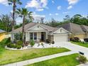 Beautiful single Gathering home with manicured lawn and stone accents, lush tropical landscaping and a two-car garage at 7410 Ambleside Dr, Land O Lakes, FL 34637