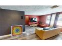 Spacious living room with wood-look flooring, neutral furniture, a large TV and colorful art at 7415 San Moritz Dr, Port Richey, FL 34668