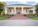 Welcoming front entrance with brick walkway, rocking chairs, and a charming porch with large white columns at 11441 Hammock Oaks Ct, Lithia, FL 33547