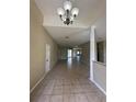 The long, open living room features gorgeous tile floors, a modern chandelier, and a neutral color palette at 13632 Deventer Ct., Hudson, FL 34667