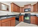 Well-equipped kitchen with wood cabinets, black appliances, and dark countertops for a modern feel at 13941 Clubhouse Dr # 308, Tampa, FL 33618