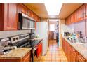 Galley kitchen featuring stainless steel appliances, tile floors, and ample cabinet space at 1512 W Sitka St, Tampa, FL 33604