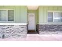 Close-up view of the front door with light green siding and stone accents on the home's facade at 16930 Sweetwater Rd, Dade City, FL 33523