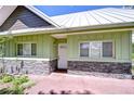 Welcoming home entrance with light green siding, stone accents, and a white front door at 16930 Sweetwater Rd, Dade City, FL 33523