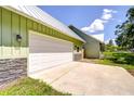 Spacious garage with a white door, light green siding, stone accents, and a metal roof at 16930 Sweetwater Rd, Dade City, FL 33523