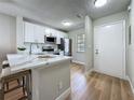 Updated kitchen with stainless steel appliances, white cabinets, stone countertops, and wood-look flooring at 1701 Pinehurst Rd # 16C, Dunedin, FL 34698