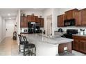 Eat in kitchen with dark wood cabinets, black appliances, and a granite countertop island at 17334 White Mangrove Dr, Wimauma, FL 33598