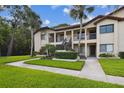 A lush green lawn and mature trees frame this condo building featuring a welcoming entrance and well-kept grounds at 1801 E Lake Rd # 3A, Palm Harbor, FL 34685