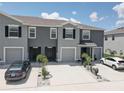 Townhomes feature a neutral gray exterior, a driveway for parking, and simple landscaping for a clean, modern look at 33062 Frosted Clover Way, Wesley Chapel, FL 33545