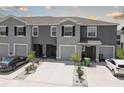 A row of gray townhomes with driveways and minimalistic landscaping featuring palm trees, small bushes, and white gravel at 33062 Frosted Clover Way, Wesley Chapel, FL 33545