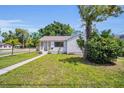 Cozy single-story home with green lawn, walkway, and mature trees on a sunny day at 4000 Grove S St, St Petersburg, FL 33705