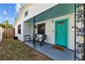 Close-up of a cozy front porch featuring a teal door, seating, and decorative metal supports at 4226 4Th S Ave, St Petersburg, FL 33711