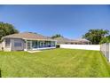 Large grassy backyard featuring a screened-in porch and a white vinyl fence at 445 Arch Ridge Loop, Seffner, FL 33584