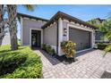 Inviting home exterior with a brick driveway, manicured bushes and lawn, and a two-car garage at 4652 San Martino Dr, Wesley Chapel, FL 33543